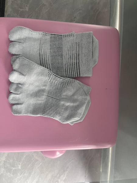 A real customer photo by Ethan showing a pair of YG Socks light grey full-coverage five-toe socks, highlighting the ribbed arch compression band for support, placed on a pink surface.