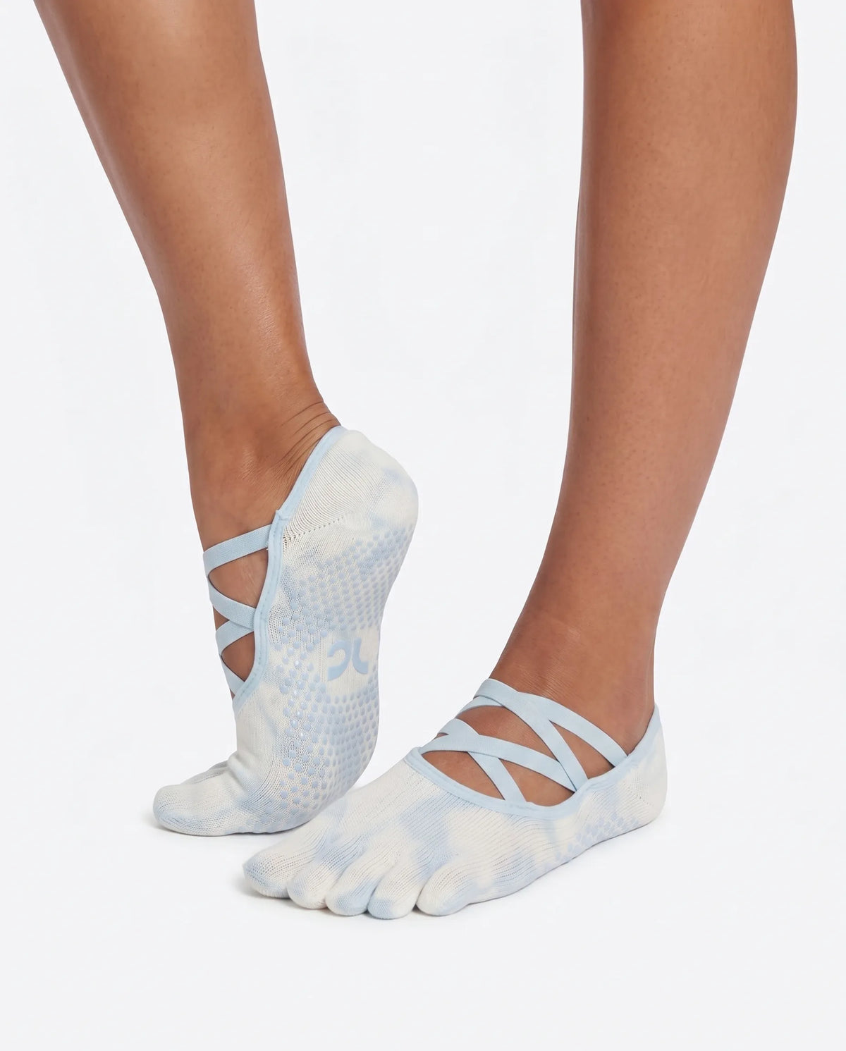 Side and back angle view of the Full Toe Cloud Wash Low Rise Grip Socks during a studio pose, highlighting the secure low-rise fit, cross straps, and grip soles.