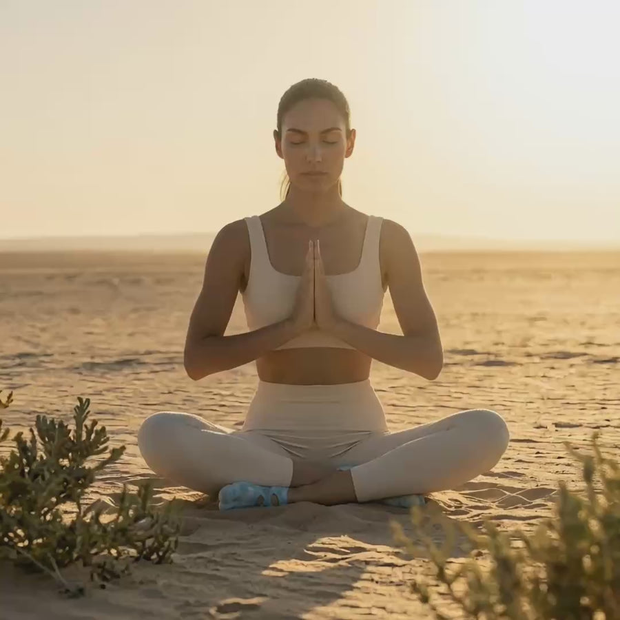 Mindful yoga movement in a vast desert landscape featuring premium tie-dye functional toe socks by YG Socks, demonstrating fluid control and secure traction on the sand.